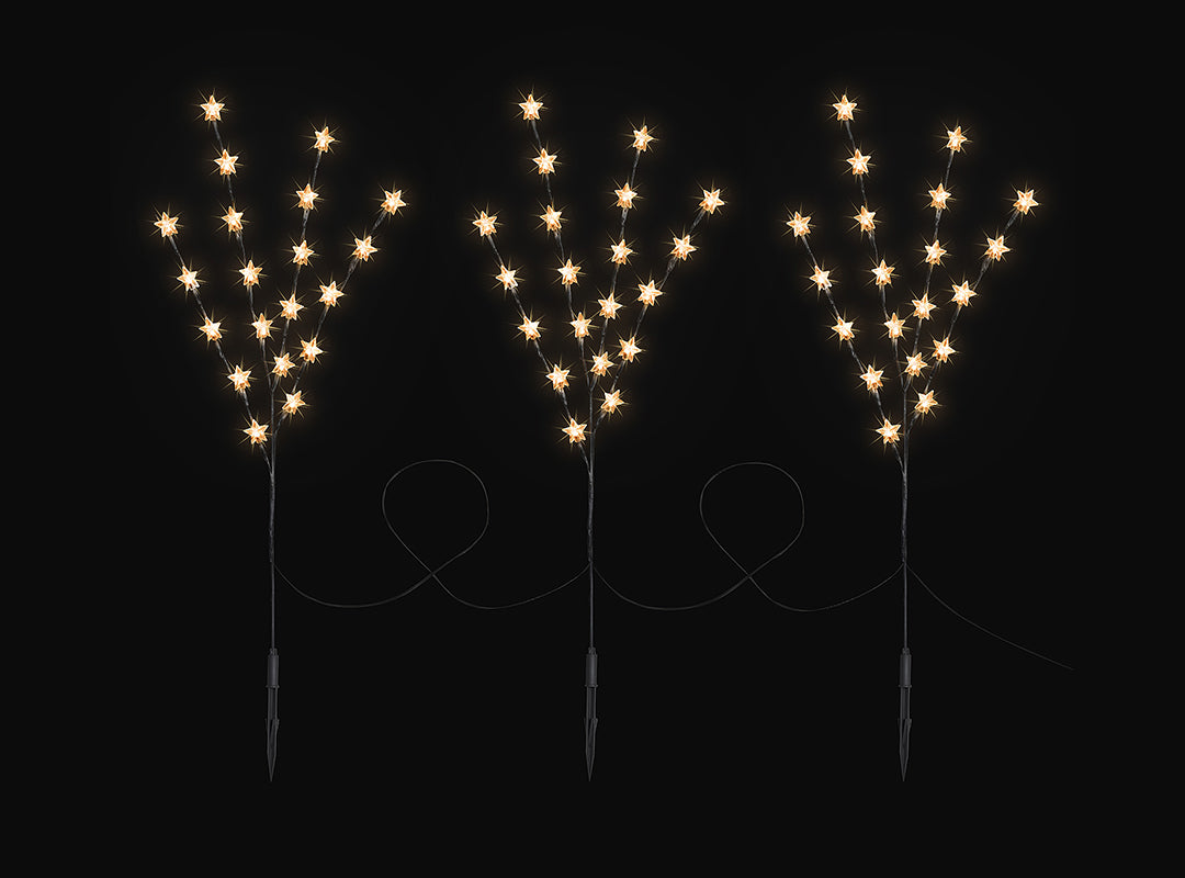 Three Christow 84cm Star Branch Path Lights glowing warm white against a dark background