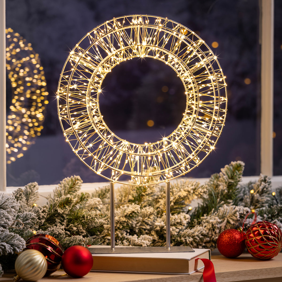 Christow Micro LED Christmas Wreath with Stand displayed with festive garland and Christmas baubles