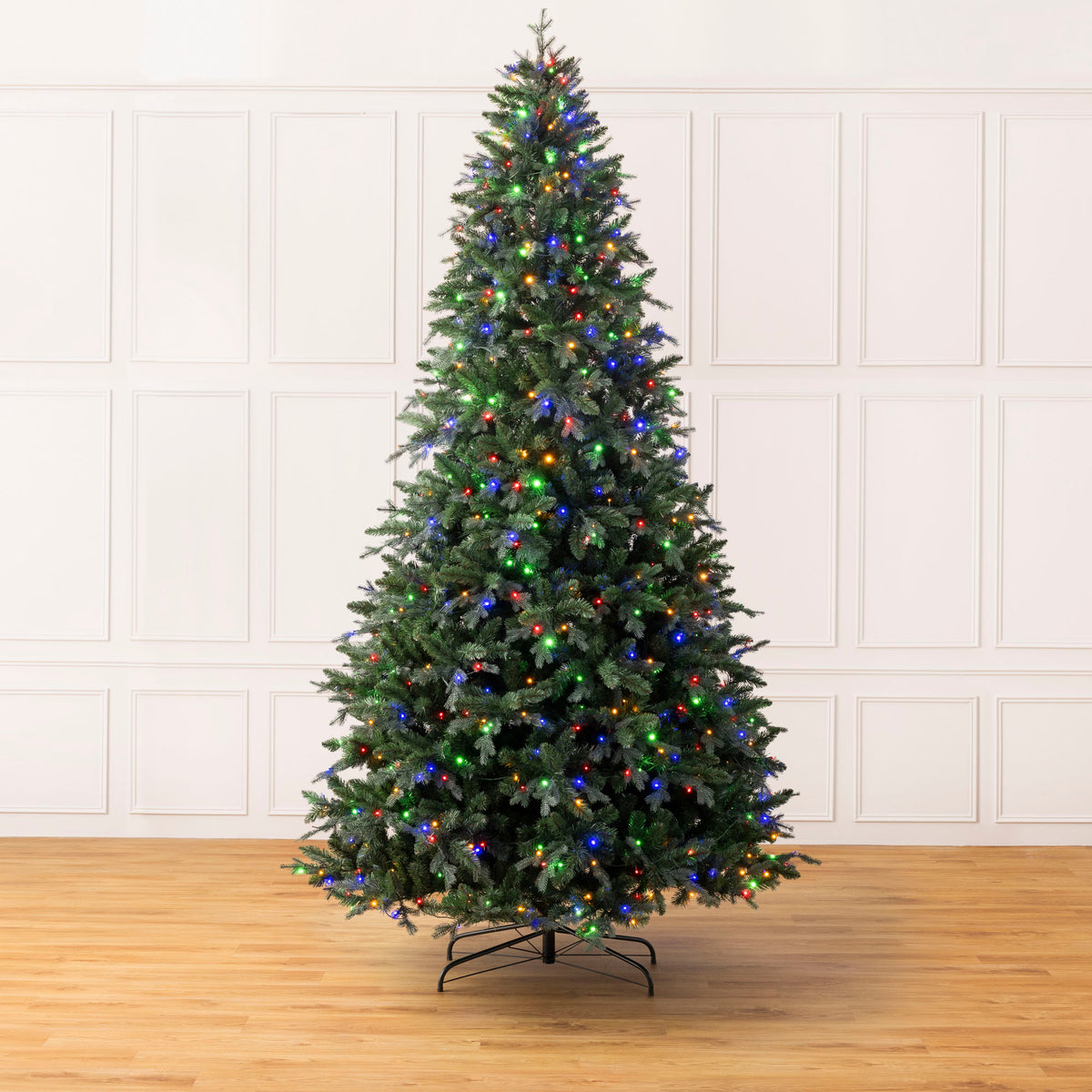 Christow Pre-Lit 10ft Fraser Fir Artificial Christmas Tree undecorated with warm white LED lights on a black metal stand against a white panelled wall