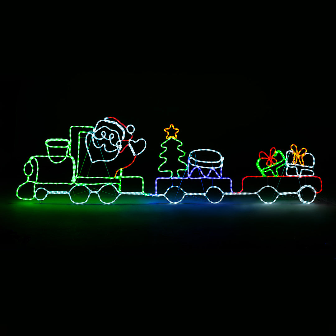 Christow Christmas Train Rope Light glowing with multi-coloured LEDs against a black background, featuring Santa waving from a green locomotive pulling two carriages carrying a Christmas tree, drum, and wrapped gifts